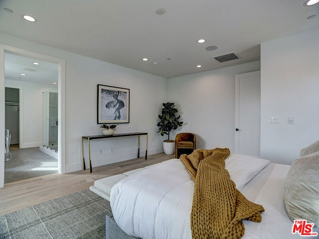 bedroom with ensuite bath and light hardwood / wood-style floors