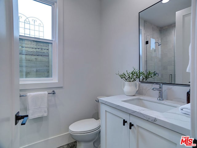 bathroom featuring toilet, vanity, and tiled shower