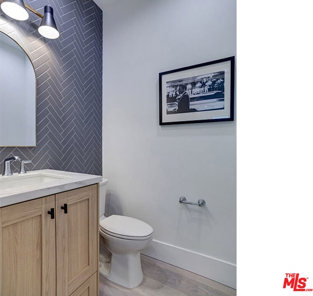 bathroom featuring backsplash, toilet, vanity, and wood-type flooring