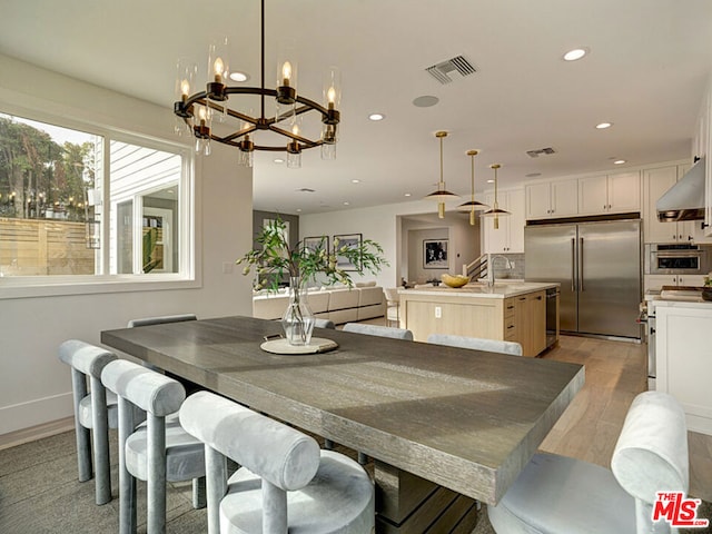 dining space featuring a chandelier, sink, and light hardwood / wood-style flooring