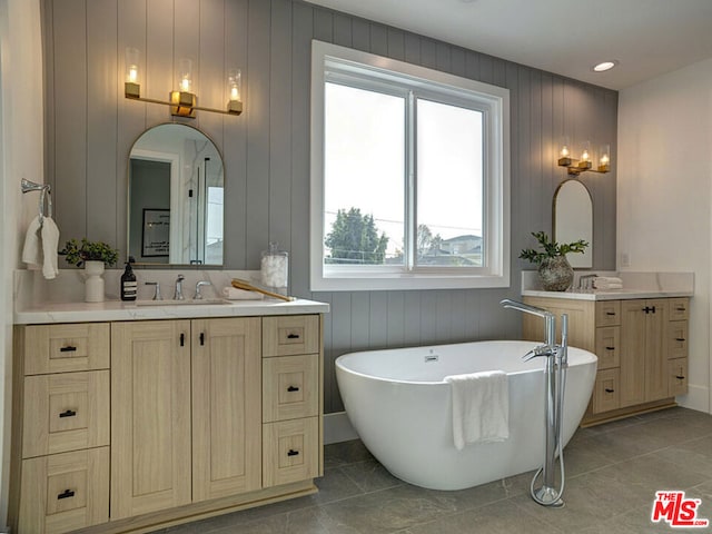 bathroom with a bath to relax in, wood walls, large vanity, and tile flooring