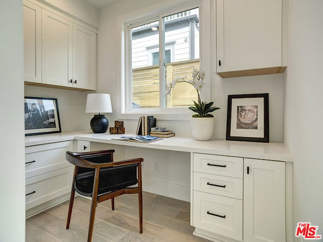 office area with light hardwood / wood-style floors, a wealth of natural light, and built in desk