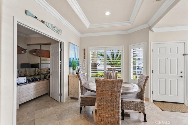 dining area with a tray ceiling, light tile patterned floors, and ornamental molding