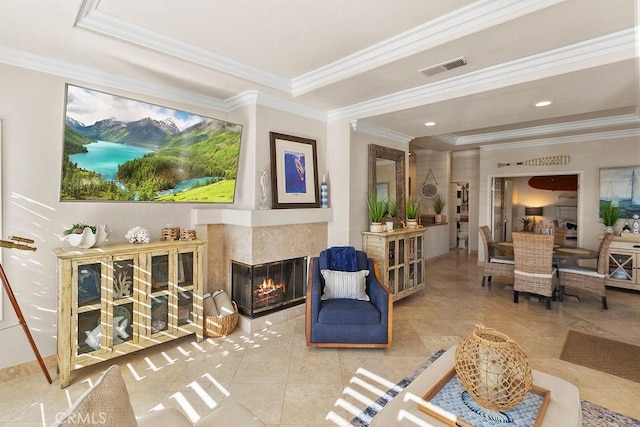 living room with a raised ceiling, crown molding, and a tile fireplace