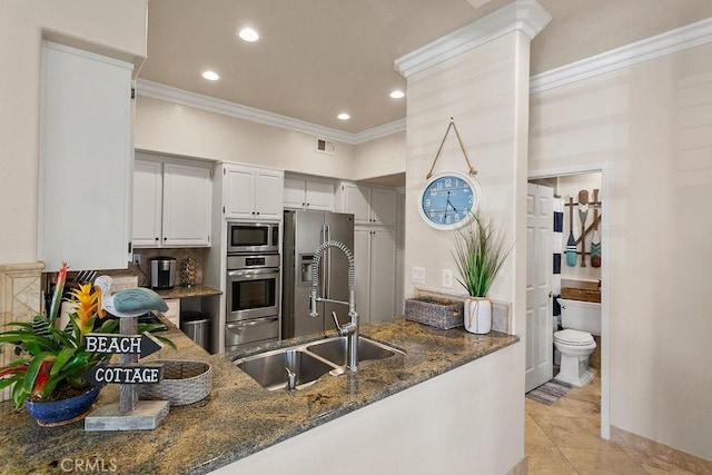 kitchen with white cabinets, crown molding, sink, dark stone countertops, and stainless steel appliances