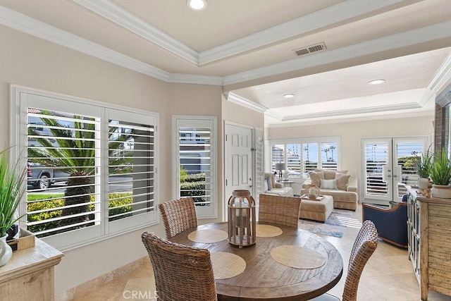 dining room featuring light tile patterned flooring, ornamental molding, and a tray ceiling