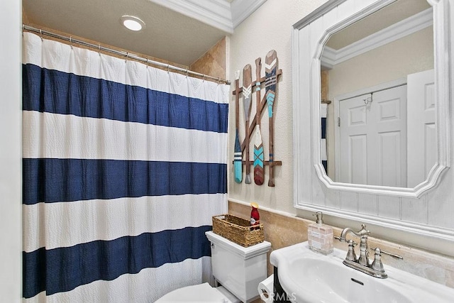 bathroom featuring toilet, curtained shower, sink, and ornamental molding