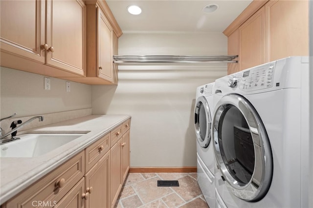 clothes washing area with sink, washer and clothes dryer, and cabinets