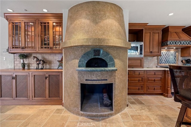 kitchen with a premium fireplace, premium range hood, stainless steel microwave, and backsplash