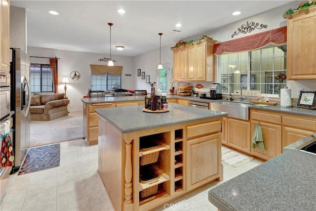 kitchen with sink, hanging light fixtures, stainless steel fridge, light brown cabinetry, and a kitchen island