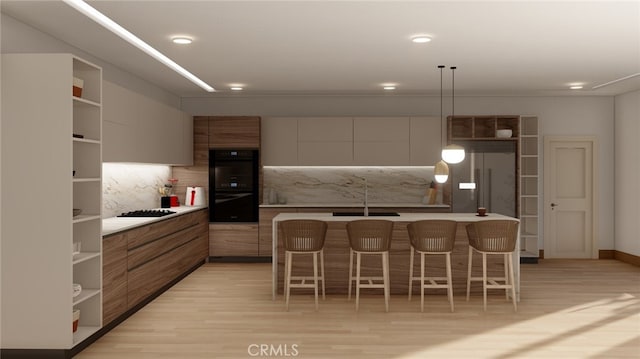 kitchen featuring light hardwood / wood-style floors, decorative light fixtures, a kitchen breakfast bar, sink, and black appliances