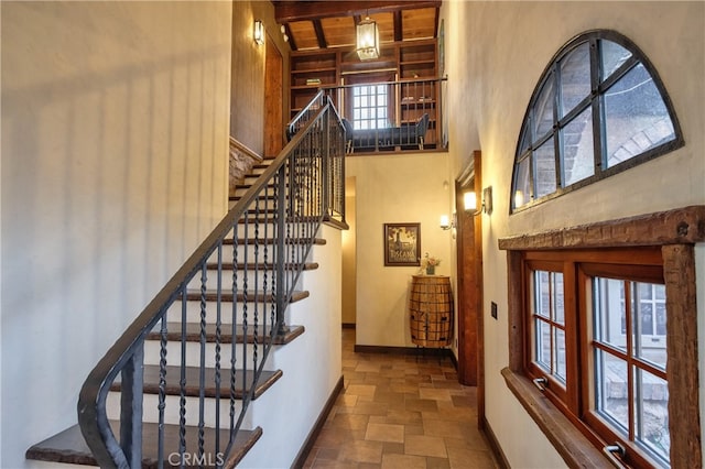 stairs featuring plenty of natural light, dark tile flooring, and a towering ceiling