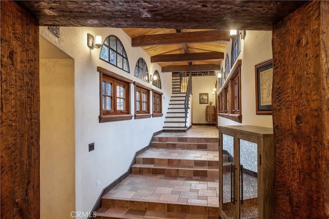 staircase featuring dark tile flooring and beamed ceiling