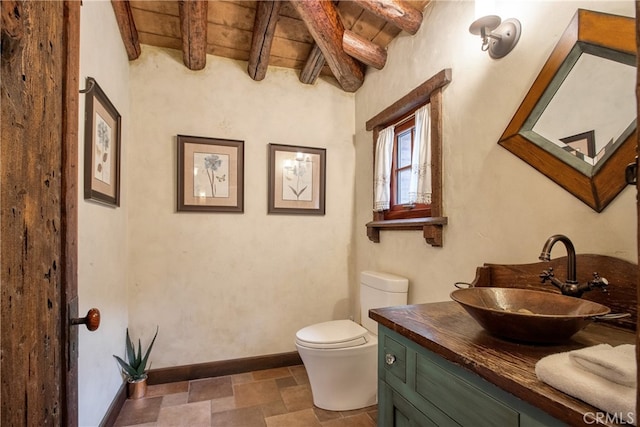 bathroom with tile flooring, toilet, large vanity, beam ceiling, and wood ceiling