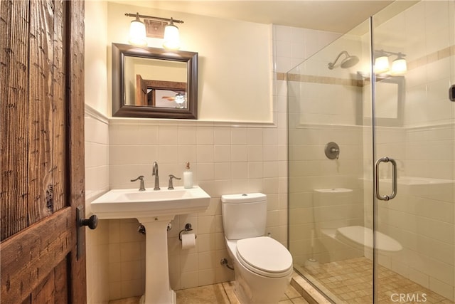 bathroom featuring backsplash, tile walls, tile floors, a shower with door, and toilet