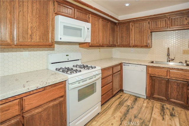 kitchen featuring white appliances, sink, light stone counters, decorative backsplash, and light hardwood / wood-style flooring