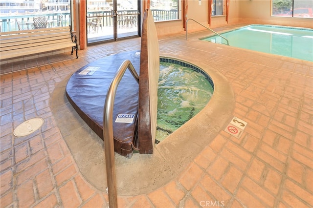 view of pool with a patio and an indoor hot tub