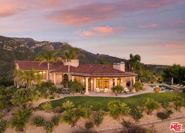 mediterranean / spanish-style house featuring a mountain view, a patio area, and a yard