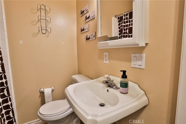 bathroom featuring a shower with curtain, toilet, and sink