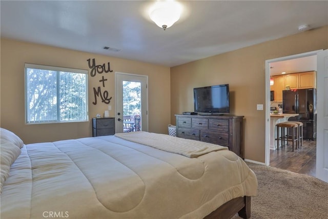 bedroom featuring access to exterior, black fridge, and light hardwood / wood-style flooring