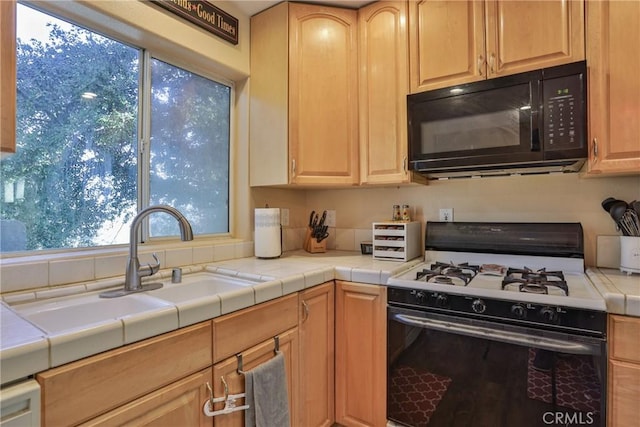 kitchen with tile countertops, light brown cabinets, white range with gas stovetop, and sink