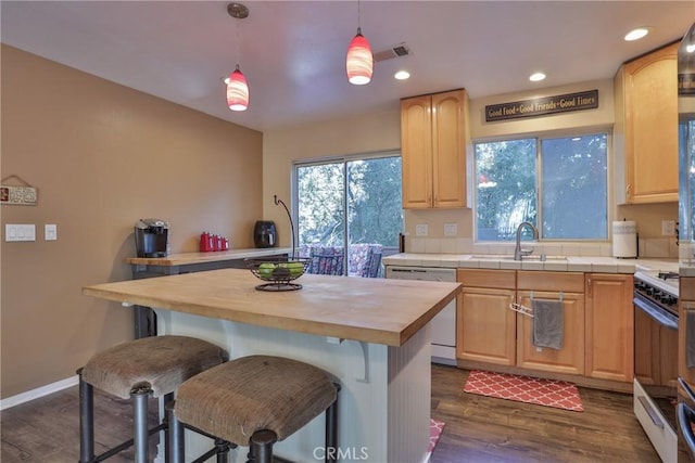 kitchen featuring white appliances, butcher block countertops, dark hardwood / wood-style flooring, a kitchen island, and a kitchen bar