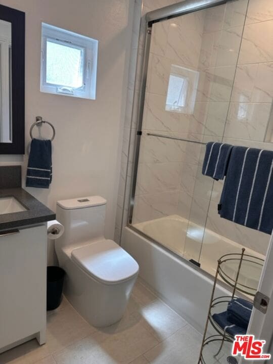 full bathroom with tile patterned floors, toilet, vanity, and bath / shower combo with glass door