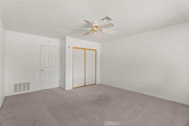 interior space featuring ceiling fan, light colored carpet, a textured ceiling, and a closet