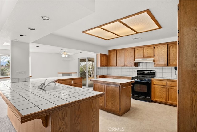 kitchen with a kitchen island, tile countertops, backsplash, kitchen peninsula, and black range with gas cooktop