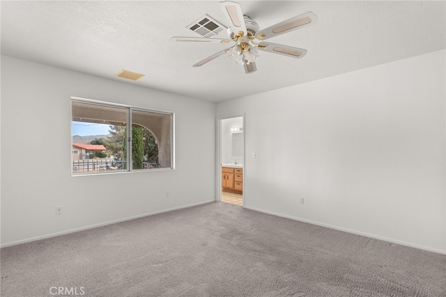 unfurnished room featuring light carpet, ceiling fan, and a textured ceiling