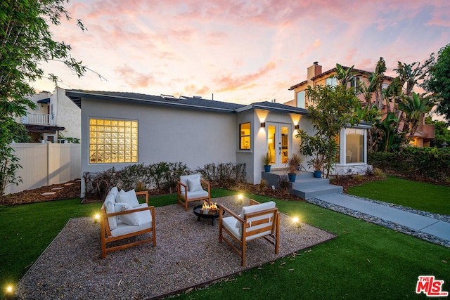 back house at dusk featuring a lawn