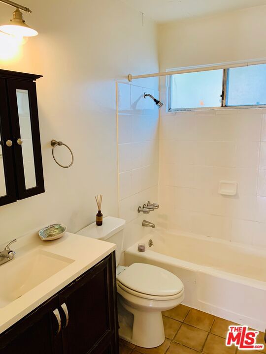 full bathroom featuring tiled shower / bath combo, tile patterned flooring, vanity, and toilet