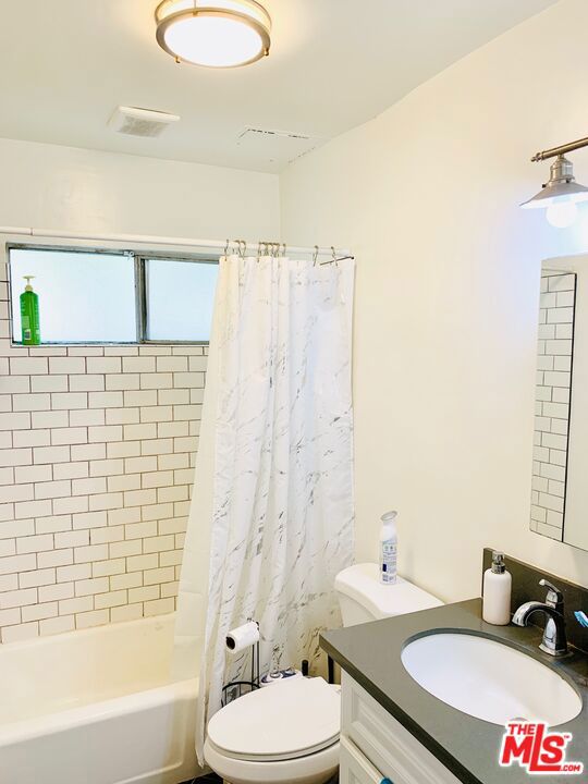 full bathroom with shower / bath combo with shower curtain, vanity, and toilet