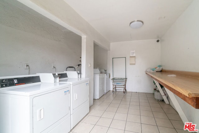 clothes washing area featuring washing machine and clothes dryer and light tile patterned floors