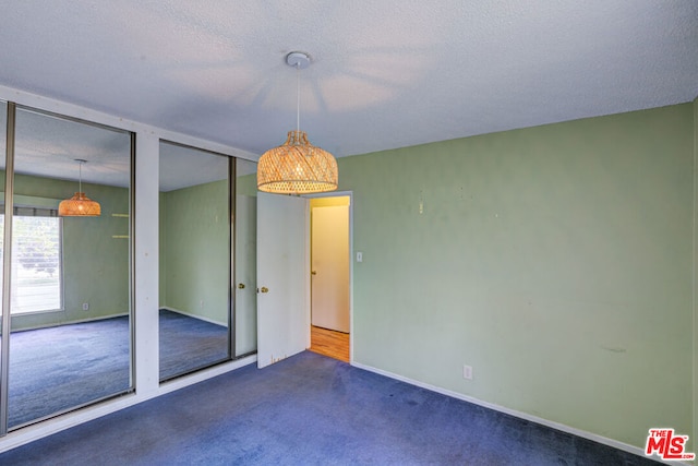 unfurnished room featuring a textured ceiling and dark colored carpet