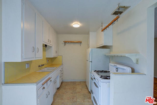 kitchen with white cabinets, backsplash, white range with gas stovetop, and sink