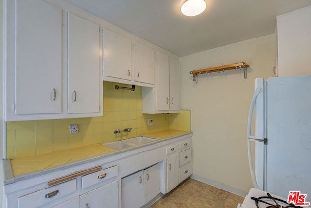 kitchen featuring white cabinetry, tile countertops, white fridge, and sink