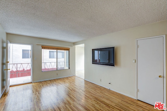 empty room with a textured ceiling and light wood-type flooring