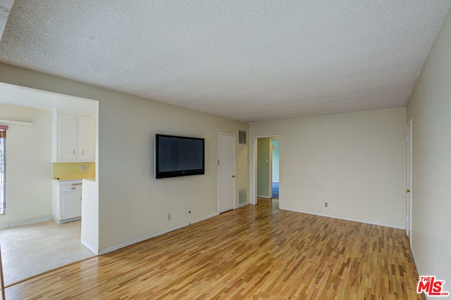 unfurnished living room with a textured ceiling and light wood-type flooring