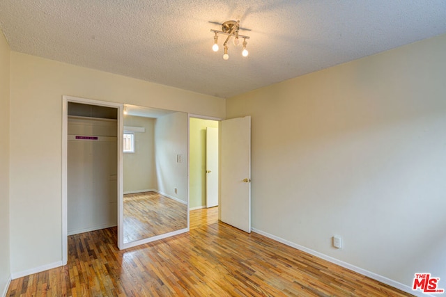 unfurnished bedroom featuring a textured ceiling, hardwood / wood-style floors, and a closet