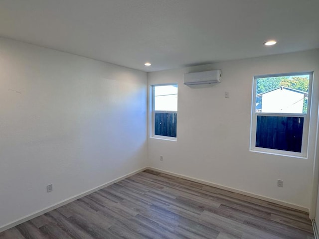 empty room featuring light hardwood / wood-style flooring, a wealth of natural light, and a wall mounted air conditioner