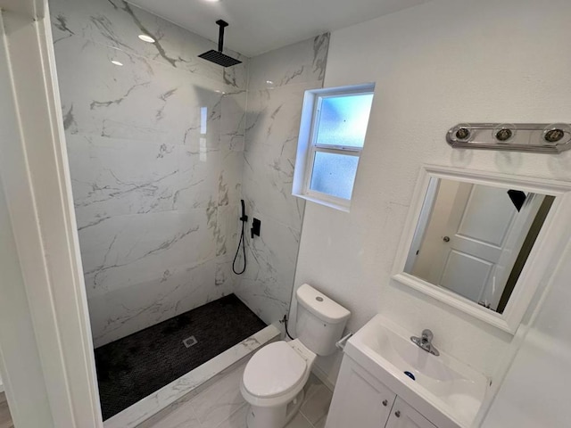 bathroom featuring toilet, tiled shower, and vanity