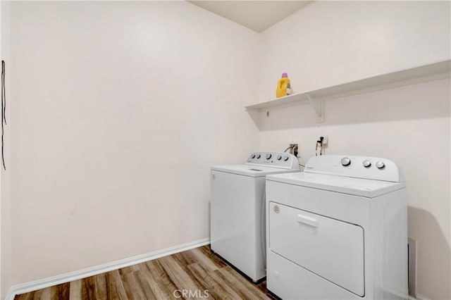 clothes washing area with light wood-type flooring and washing machine and clothes dryer