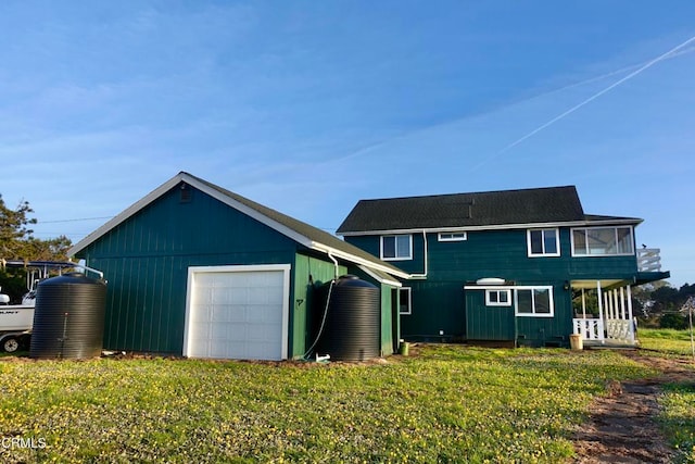 back of house featuring covered porch, a yard, and a garage