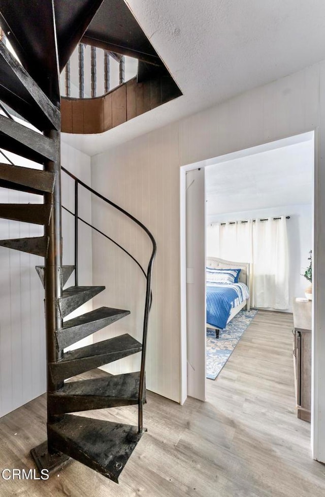 stairs with wood walls, a textured ceiling, and hardwood / wood-style flooring