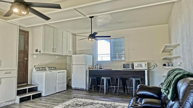 clothes washing area with ceiling fan, washing machine and dryer, and dark hardwood / wood-style flooring