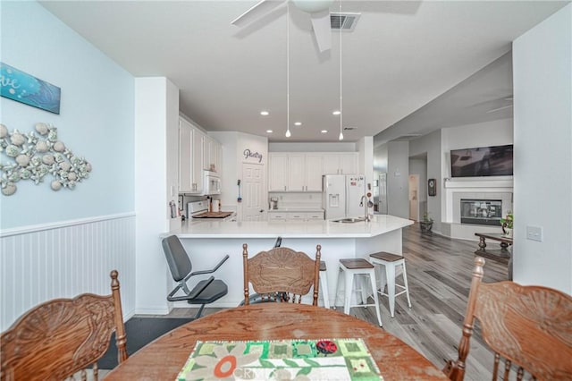 kitchen featuring white appliances, dark wood-type flooring, white cabinetry, sink, and kitchen peninsula