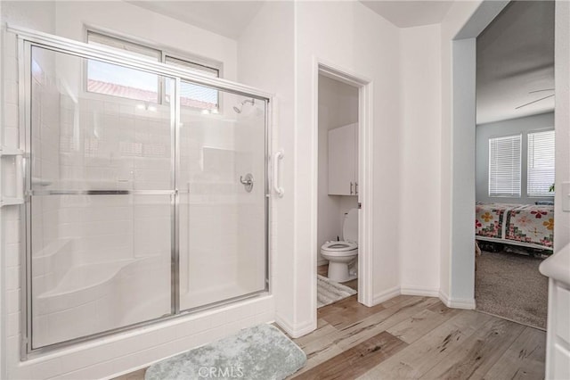 bathroom featuring toilet, hardwood / wood-style floors, plenty of natural light, and an enclosed shower