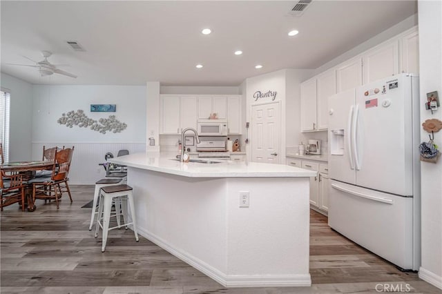 kitchen featuring sink, hardwood / wood-style floors, white appliances, and white cabinets