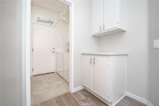 clothes washing area with washing machine and dryer and light hardwood / wood-style floors